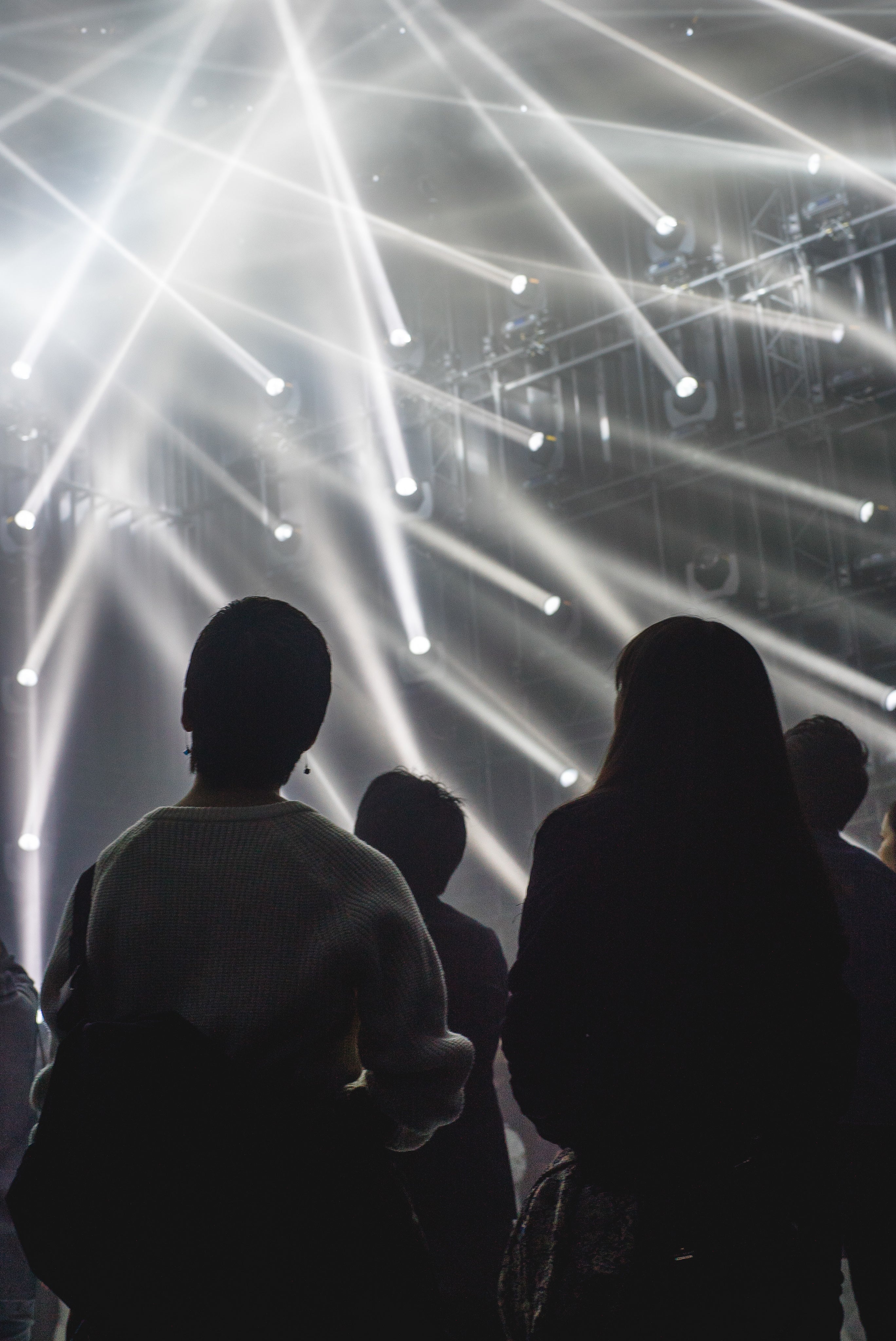 People looking at light beams at a concert